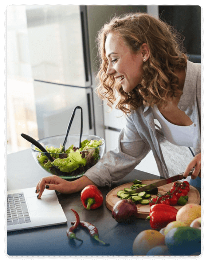 woman cooking and looking on computer