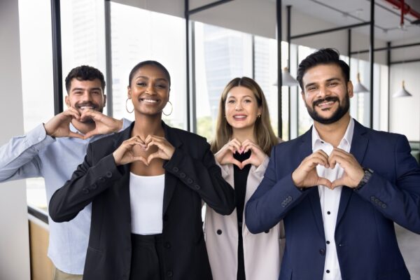 A group of people in an office with hands making the shape of a heart.