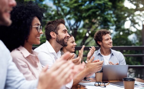 A group of people looking at something off camera while clapping.