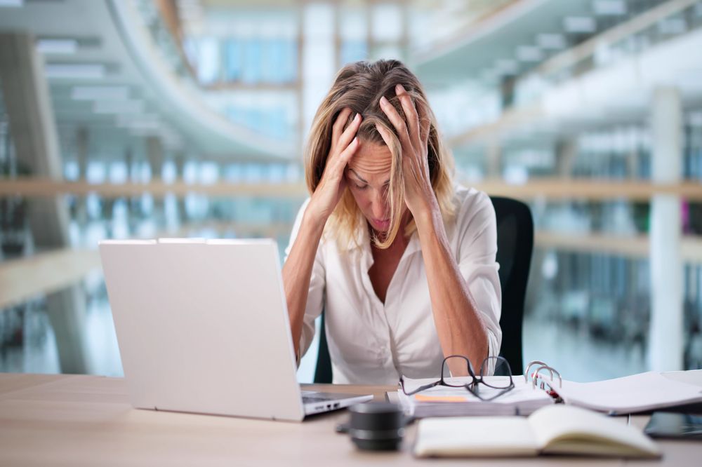 Woman at work looking stressed over computer